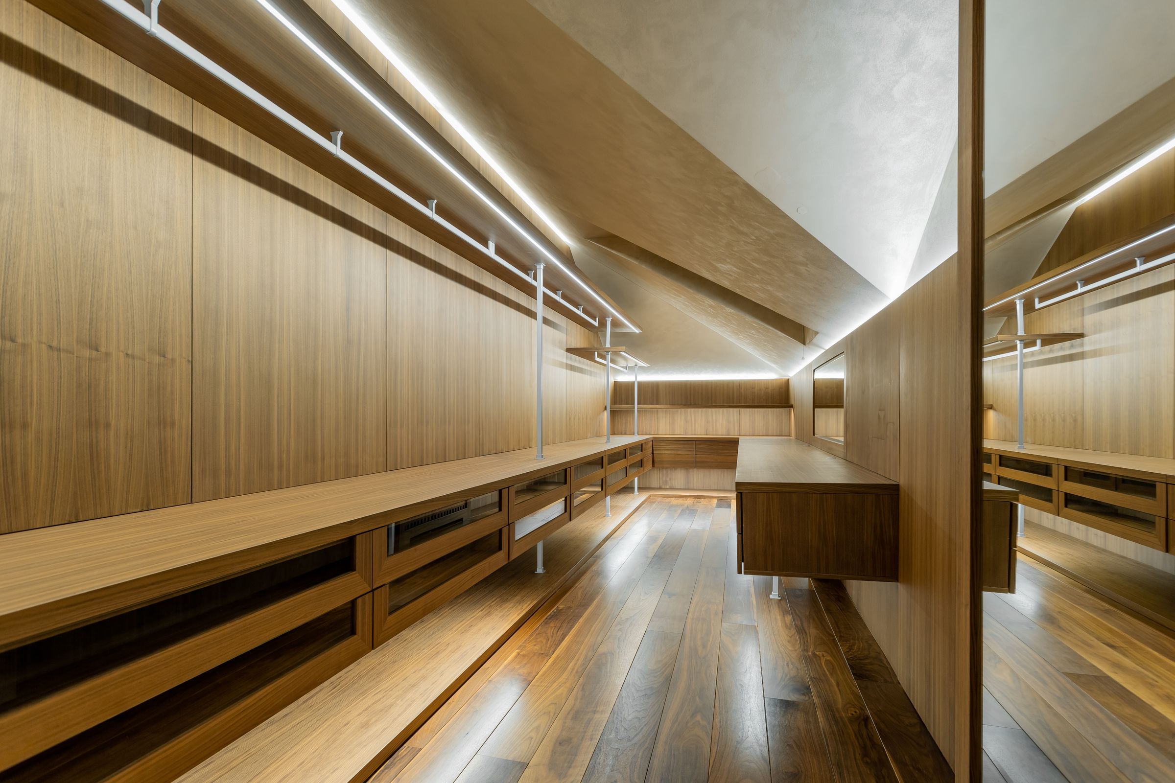 Walnut walk-in closet with integrated linear lighting